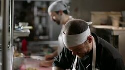 Professional chef cuts thick tuna steak on prep table in busy kitchen restaurant Stock Footage
