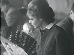 1963: BERLIN '63: People sitting on long bench, some college age, ZI young adult female (iconic 60s look) sitting, reading. Instructional Video