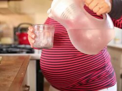 A pregnant women eating and drinking in healthy ways inside of her kitchen. Stock Footage