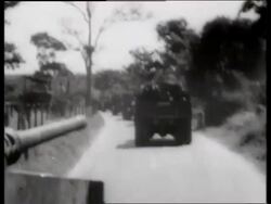 B/W 1960's tank point of view behind trucks on dirt road / Vietnam / SOUND Stock Footage