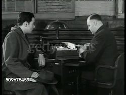 1944: U.S. VETERANS EMPLOYMENT SERVICE: DRAMATIZATION: INT VS Male veteran sitting at desk w/ man '... you take this slip over to Bishop's. They need a man in the tool checking, I know you're qualified...' MS Man leaving w/ slip. Jobs, Post WWII Instructional Video