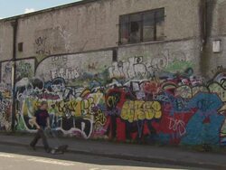 WS View of people walking on street near painted wall / Dublin, Ireland Stock Footage