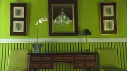 A chandelier reflects in a mirror hanging on a wall next to two paintings. Stock Footage