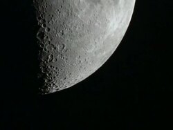 Close-up on the lower part of the first quarter moon as it slowly moves across the frame. Details of the surface and craters are visible. Stock Footage