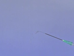 Liquid squirting from Syyringe against Blue Background, Slow motion Stock Footage