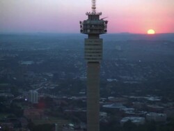 Aerial of the Hillbrow Tower moving further away to reveal Johannesburg Central Business District at sunset/sunrise Stock Footage