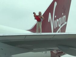 Sir Richard Branson carries singer Sarah Harding on wing of jet Stock Footage