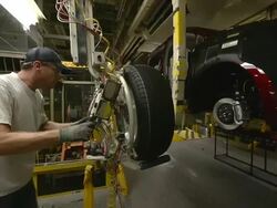 MS PAN Worker using an mechanical assist to installing wheel and tire on minivan in an auto assembly plant / Princeton, Indiana, United States Stock Footage