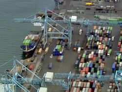 Aerial wide shot pan cargo ship moored at dock with crane and stacked containers/ Dublin, Ireland Stock Footage