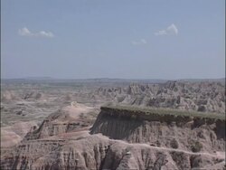 WA jagged rocky landscape stretching to horizon, blue sky, white clouds, Bad Lands, South Dakota, USA Stock Footage