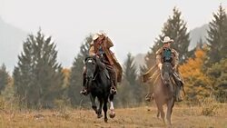SLO MO DS Herdsman and herdswoman enjoying galloping horseback ride Stock Footage