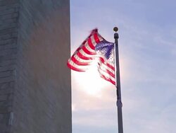 A static shot with a lens flare of an american flag to the side of the Washington Monument. Stock Footage