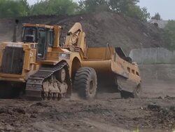 Caterpillar construction vehicles maneuver around construction site Stock Footage