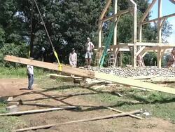 WS PAN ZO Carpenters and crane operator slowly moving part of structure during framing of an energy efficient post / Grass Lake, Michigan, USA  Stock Footage