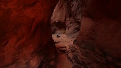 Camera travels through narrow red-rock canyon to reveal repelling group repelling down steep canyon wall in Utah Stock Footage
