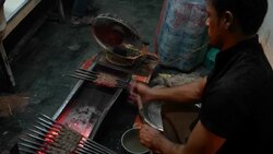 A man prepares meat kebabs in an open charcoal grill in streets of Old Delhi during the nighttime Stock Footage
