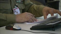 A uniformed officer with ribbon bars processes paperwork at a desk. Stock Footage