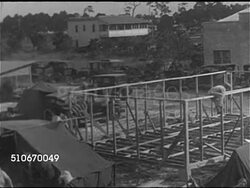 1920s: FLORIDA LAND BOOM: HA WS Crowd of men gathered around salesman, CU Print ad for west coast of Florida land ($7500 acre), HA PAN Neighborhood w/ homes partially completed, residents w/ tents, camping, women washing clothes in large metal tubs. Instructional Video