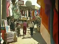 WA people walking through street market, colourful scarves and clothes displayed, Egypt Stock Footage