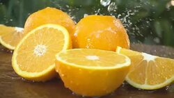 Orange and water splash slow motion on a green background Stock Footage