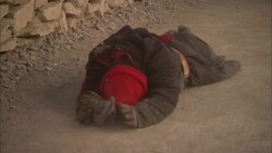 A Tibetan citizen genuflects then prostrates himself in the dirt and prays. Stock Footage