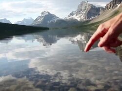 Person's finger touches surface of mountain lake Stock Footage