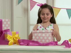 Girl opening present of feather boa and teddy bear Stock Footage