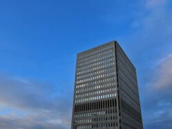 T/L ofdusk approaching single office tower Stock Footage