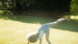 Girl doing cartwheel in sunny backyard Stock Footage