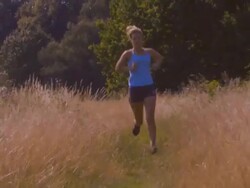 Woman running through field; UK Stock Footage