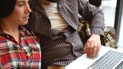young couple sitting on sofa and using gadgets Stock Footage