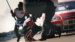 Pit-crew removes lug-nuts and jacks race-car, man runs with tire Stock Footage