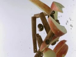 Apple and cinnamon sticks collide mid-air Stock Footage