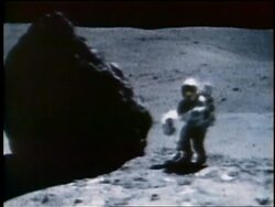 1972 astronaut taking soil sample by large boulder then bouncing away on Moon / Apollo 16 Stock Footage