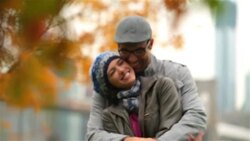 New York couple in love hold each other and kiss sweetly in park, autumn leaves in foreground (dolly-shot) Stock Footage