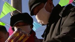 Shoppers with face masks select fireworks from a Panda Shop vendor in Beijing, China. Stock Footage