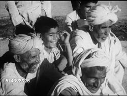 1953: PAKISTAN: VS Pakistani people, two musicians playing musical instruments (long rhythm stick & one w/ two flutes) outdoors for seated village group, men & boy smiling, laughing, VS Musician playing, other singing, SOT [partially out of sync]. Instructional Video