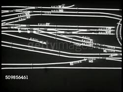 1947: U.S. TRAIN COMMUNICATIONS: INT WS Man standing operating train control board switches. CU Railroad train lines on wall w/ lights. (POV Train) Moving under signal bridge. CU Signal inside train cab. MS Engine man picking up radio telephone. USA Instructional Video