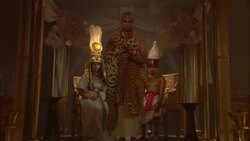 A priest in a leopard skin robe holds incense as he leads Egyptian royalty out of a throne room. Stock Footage