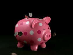 CU SLO MO Coins being dropped onto pink polka dot piggy bank / Studio, New Jersey, USA Stock Footage