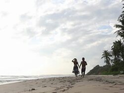 Family walk along beach together, kids run in front Stock Footage