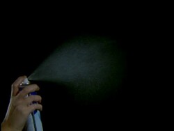 High Speed Aerosol, hand holding can, sprays fine white mist into air against black background Stock Footage