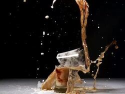 MS SLO MO Glass of beer breaking and splashing against black background / Vieux Pont, Normandy, France Stock Footage