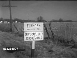 1952: ELKHORN, WISCONSIN: DRIVING: WS DRIVING On rural country road, approaching sign, 'Elkhorn, population 2935, Drive Carefully, School Zones.' CU Hand circling 'Elkhorn' on map, Wisconsin, hand showing distance between Elkhorn & Chicago, Milwaukee. Instructional Video