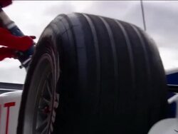 Low angle medium shot zoom in pit crew refueling Formula One race car during pit stop / car driving off Stock Footage