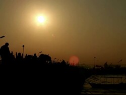 Early morning crowds silhouetted against dawn sky as they walk slowly across pontoon bridge.  Kumbh Mela, India Stock Footage