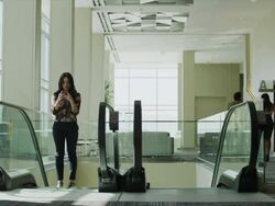 Panning shot of businesswoman ascending on escalator then tripping in office lobby / Provo, Utah, United States,  Stock Footage