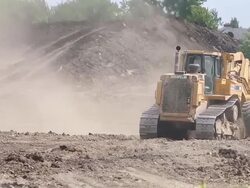 A Caterpillar construction vehicle excavates soil at a building site Stock Footage