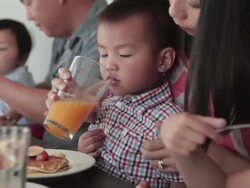 MS Shot of Chinese family eating together with boy drinking orange juice / Los Angeles, California, United States  Stock Footage