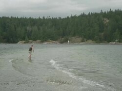 MS SLO MO PAN Woman walks along bank with waves breaking along shore / Cortes, British Columbia, Canada  Stock Footage